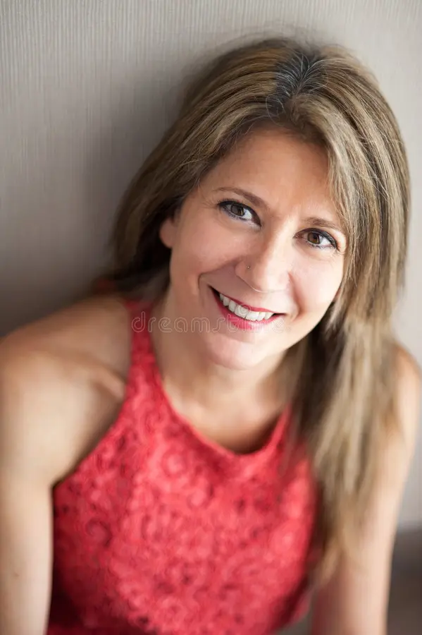 A middle aged woman smiling confidently, reflecting natural vitality and optimized feminine health balance